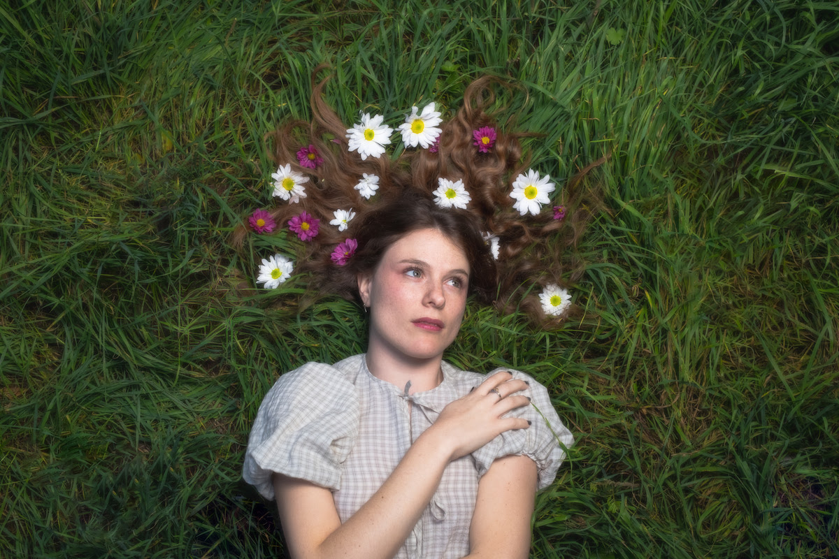 Singer songwriter Danxgerous lying on grass with flowers in hair for The Unsigned Guide Spotlight July 2026 feature